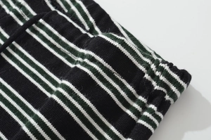Close-up of green and black striped knit fabric with detailed stitching and elastic waist