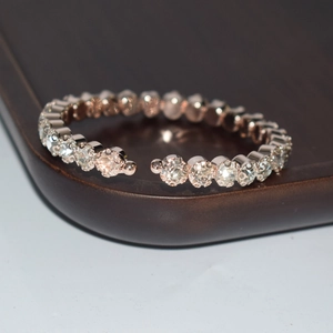 Detail of rose gold open bangle with single row of shimmering rhinestones on a tray