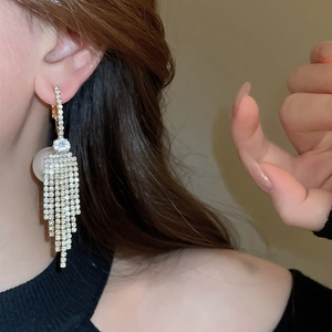 Detail of golden tassel earrings with sparkling rhinestones and pearl backing on model