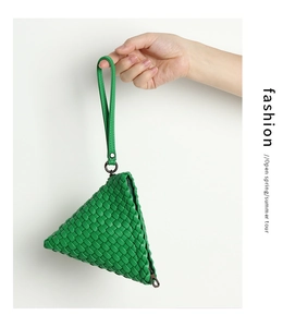 Macro shot of a grass green hand-woven triangle wristlet with matte finish and metal zipper