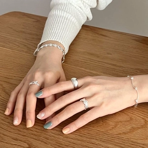 Detailed view of irregular S925 silver rings and layered beaded bracelets on hand