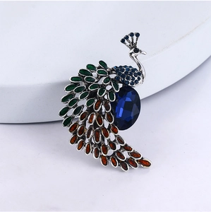 Détail d'une broche paon avec cristal bleu foncé et plumes en émail coloré