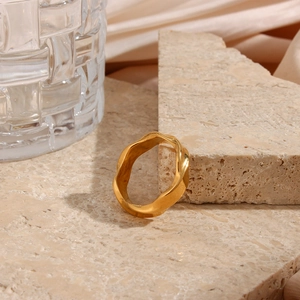 Macro shot of 18K gold plated stainless steel wave ring on a textured stone surface