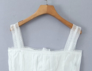 Close-up of white lace shoulder straps and pleated cotton fabric details on the top