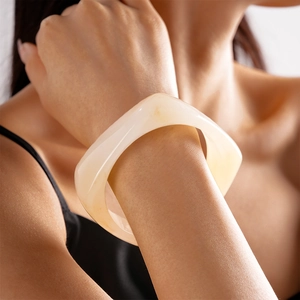 Close-up of a wide geometric resin bangle in creamy white on a model wrist