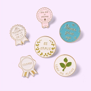 Set of 6 colorful enamel lapel pins with inspirational quotes like Be Brave on purple background