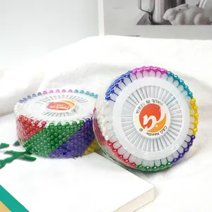 Colorful pearlized head sewing pins arranged in white plastic discs on textured fabric