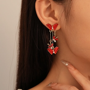 Macro shot of elegant red crystal butterfly tassel earrings with gold metal and rhinestones