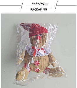 Detail of Christmas gingerbread man plush toy in plastic packaging with festive red hat