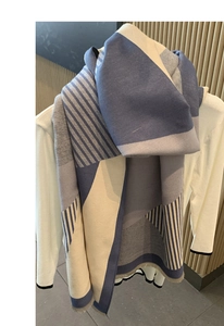 Close-up of geometric knit scarf with blue-grey patchwork and fringe detail
