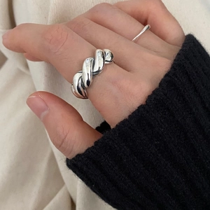 Close-up of minimalist chunky silver twisted knot ring worn by model on a white background