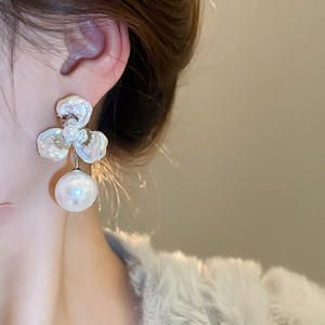Close-up of a floral petal stud earring with a large round pearl on a model