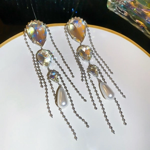 Detailed view of silver tassel earrings with crystal drops and white pearls on a tray