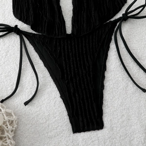 Detailed view of black textured fabric with side ties and high-cut swimsuit design