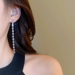 Dettaglio macro di un orecchino con nappa in zircone su modella per un look di lusso