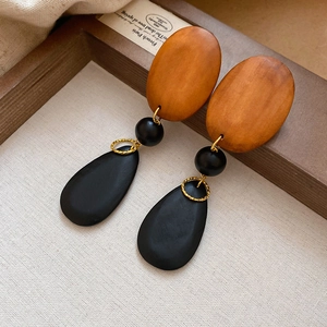 Detail view of oval wood drop earrings featuring orange and black geometric beads