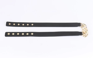 Detail of black leather belt with gold round studs and heavy metal chain buckles