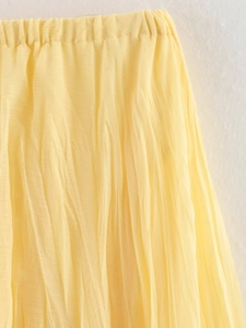 Détail de la taille élastique et de la texture plissée sur une jupe jaune pâle
