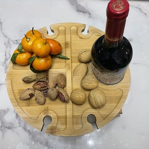 Top view of a round wooden picnic tray with 4 wine glass slots and divided snack sections