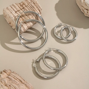Close-up of three sizes of silver hoop earrings on natural stone for a minimalist look