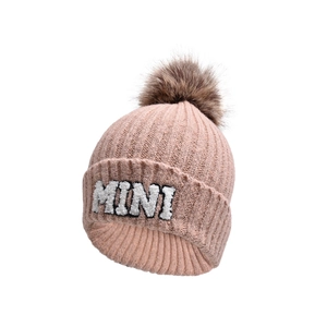 Detail of pink knitted beanie with MINI embroidery and large faux fur pompom