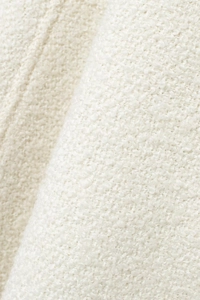 Close-up of white bouclé textured fabric detail for elegant stand collar cape coat