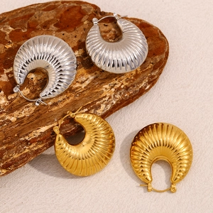 Detail shot of hollow 18K gold and silver hoop earrings with vertical ribbed texture