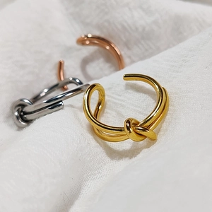 Detailed view of knot design open rings in gold, silver, and rose gold finishes
