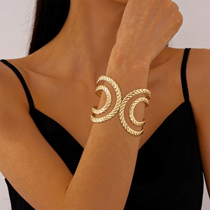 Macro detail of golden twisted texture and layered wide open bangle on woman's wrist