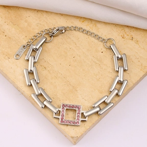 Macro detail of silver rectangular link bracelet featuring a pink zircon pendant and K18 tag