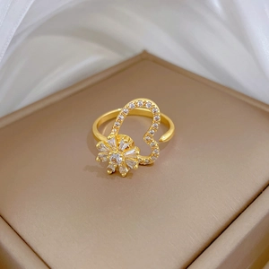 Detail of adjustable gold ring featuring a spinning flower design and zircon inlay
