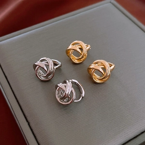 Close-up of minimalist entwined knot hoop earrings in polished gold and silver finishes