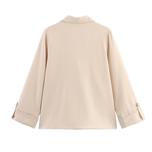 Detail of elegant beige shirt sleeves featuring refined pearl button cuffs and smooth texture