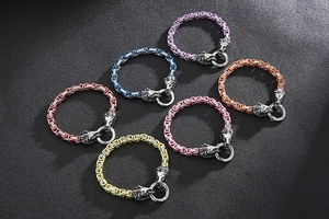 Multi-color stainless steel lion head bracelets in red, blue, and yellow on black texture