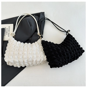 Detailed view of white and black bubble textured fabric on pleated underarm bags