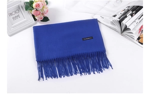 Detailed shot of a blue cashmere scarf featuring classic fringe on a styled desktop