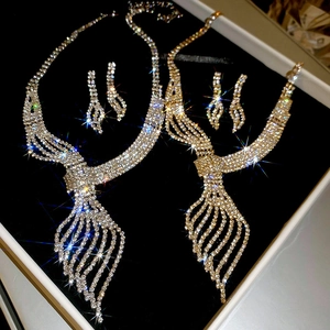 Detailed view of silver and gold leaf necklaces with rhinestone tassels in gift box