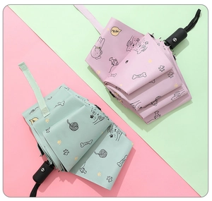 Detailed view of pink and mint green folding umbrellas with cute cartoon pet patterns