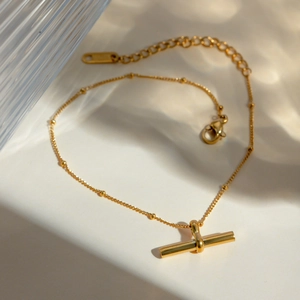 Detail of 18K gold bead chain anklet with smooth T-bar pendant and lobster clasp