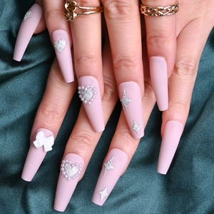 Close-up of pink long coffin press-on nails with white 3D bows and silver glitter hearts