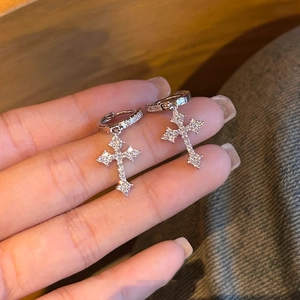 Elegant silver cross earrings with sparkly cubic zirconia crystals held in hand