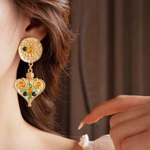 Macro detail of vintage matte gold floral earring with colorful heart resin stones