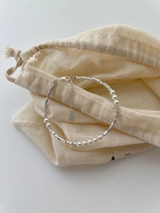 Detail of S925 sterling silver beads and pearls on a beige linen pouch with lobster clasp