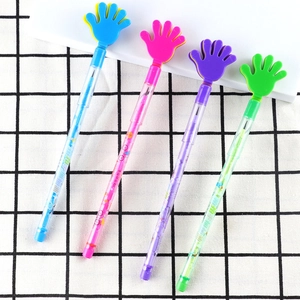 Detail of four colorful plastic pencils with hand-shaped tops on a black and white grid cloth