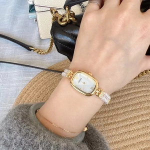 Detailansicht goldene ovale Damenuhr mit zweireihigem Perlenarmband am Handgelenk