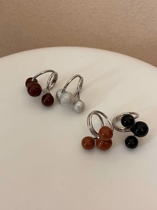Detailed view of spherical drip oil rings in four colors on a white minimalist display