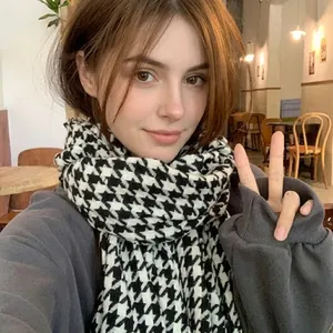 Close-up of a classic black and white houndstooth knit scarf styled on a person
