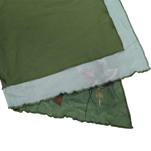Détail d'une robe en tulle vert montrant le tissu double couche et l'ourlet ondulé