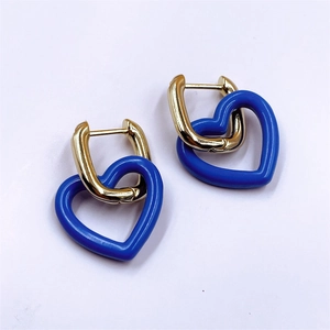 Détail de boucles d'oreilles en U dorées avec pendentifs en forme de cœur bleu roi