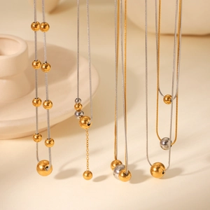 Detail of dual-layer stainless steel snake chain with gold and silver bead pendant
